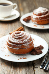 Cinnamon buns on plate with coffee on grey wooden background