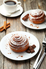Cinnamon buns on plate with coffee on grey wooden background