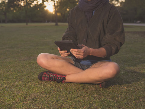 Woman using tablet in park at sunset