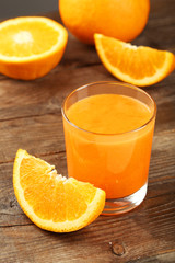 Orange fruit and glass of juice on brown wooden background
