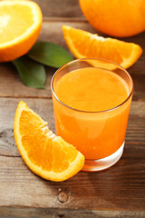 Orange fruit and glass of juice on brown wooden background