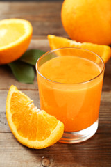 Orange fruit and glass of juice on brown wooden background