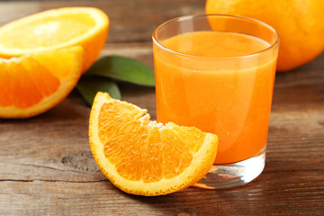 Orange fruit and glass of juice on brown wooden background
