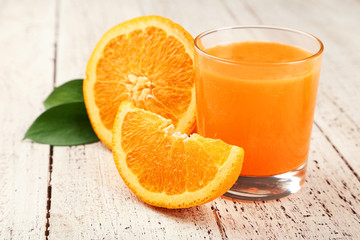 Orange fruit and glass of juice on white wooden background