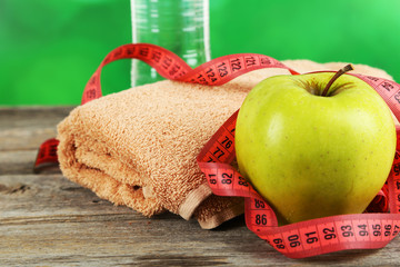 Green apple with measuring tape and glass of water