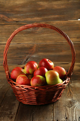 Beautiful apples in basket on brown wooden background