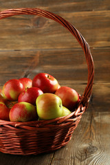 Beautiful apples in basket on brown wooden background