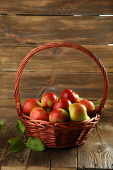 Beautiful apples in basket on brown wooden background