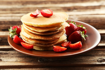 Delicious pancakes with strawberry on brown wooden background