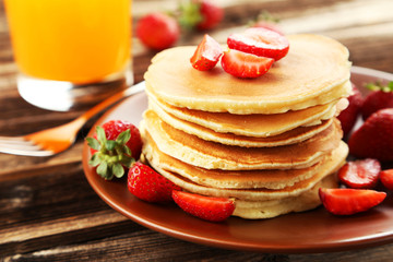 Delicious pancakes with strawberry on brown wooden background