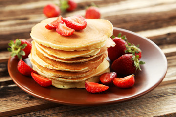 Delicious pancakes with strawberry on brown wooden background