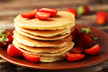 Delicious pancakes with strawberry on brown wooden background