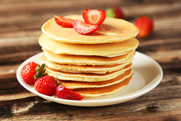 Delicious pancakes with strawberry on brown wooden background