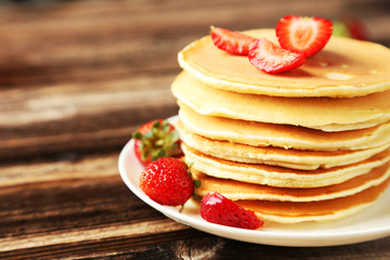 Delicious pancakes with strawberry on brown wooden background