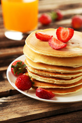 Delicious pancakes with strawberry on brown wooden background