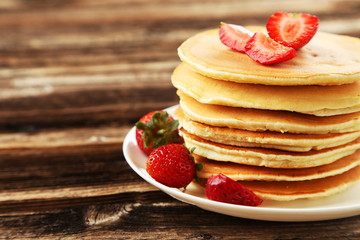 Delicious pancakes with strawberry on brown wooden background