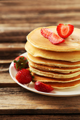 Delicious pancakes with strawberry on brown wooden background