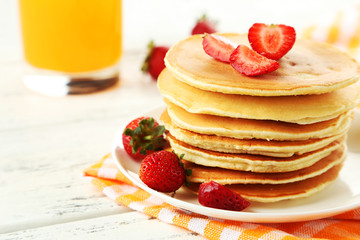 Delicious pancakes with strawberry on white wooden background