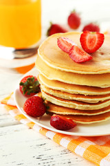 Delicious pancakes with strawberry on white wooden background