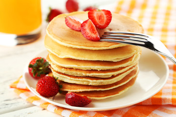 Delicious pancakes with strawberry on white wooden background