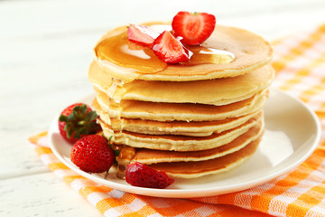 Delicious pancakes with strawberry on white wooden background