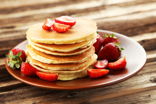 Delicious pancakes with strawberry on brown wooden background
