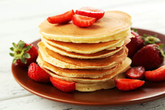 Delicious pancakes with strawberry on white wooden background