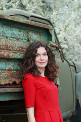 Blue-eyed brunette at old truck body and blooming fruit trees