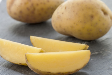 Cut potatoes close up raw on black background