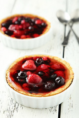 Fresh berry tarts on white wooden background