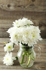 White chrysanthemum flowers in jug on grey wooden background