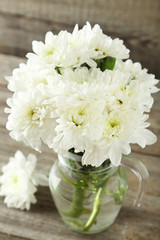 Fototapeta na wymiar White chrysanthemum flowers in jug on grey wooden background