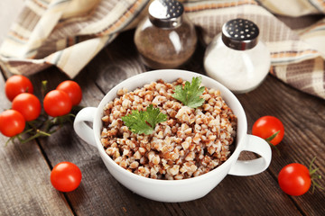Buckwheat in bowl on brown wooden background