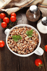 Buckwheat in bowl on brown wooden background