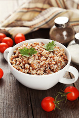 Buckwheat in bowl on brown wooden background