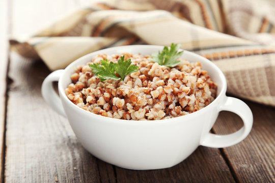 Buckwheat in bowl on brown wooden background