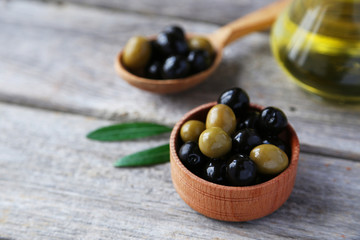 Green and black olives in bowl on grey wooden background