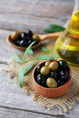 Green and black olives in bowl on grey wooden background
