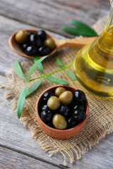 Green and black olives in bowl on grey wooden background