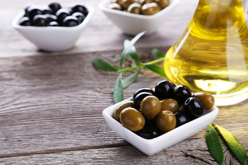 Green and black olives in bowl on grey wooden background