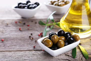 Green and black olives in bowl on grey wooden background