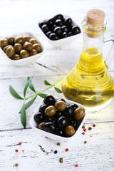 Green and black olives in bowl on white wooden background