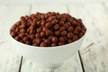 Bowl of cornflakes on white wooden background