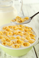 Bowl of cornflakes with milk on white wooden background