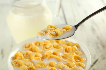 Bowl of cornflakes with milk on white wooden background