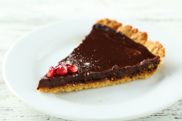 Chocolate tart with pomegranate on wooden background