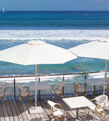 Fototapeta na wymiar tables en terrasse au bord de l'océan 