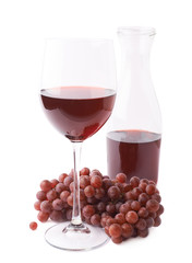 Glass of red wine next to a branch of grapes