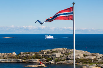 Norwegian flag with a small red cabin and an unmarked ferry