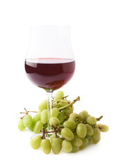 Glass of red wine next to a branch of grapes